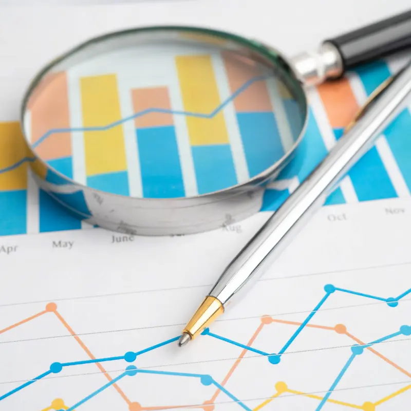 Magnifying glass laying on paper that has charts on it